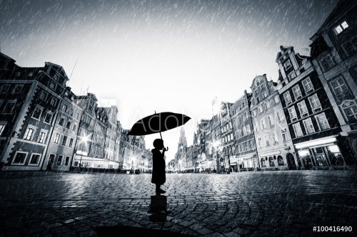 Child with umbrella standing alone on cobblestone old town in rain - 901146469
