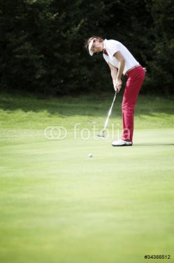 Female golfer putting - 900184526