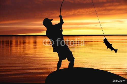 fisherman with a catching fish on sunrise background - 900181097