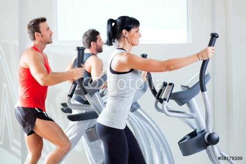 man and woman with elliptical cross trainer at gym - 900345495