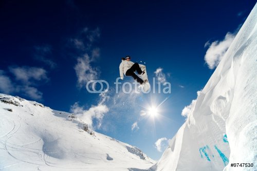 Snowboarder jumping through the air with blue sky background