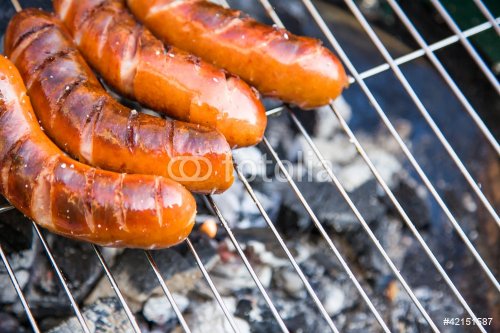 Tasty sausages burning on hot barbeque - 900437750