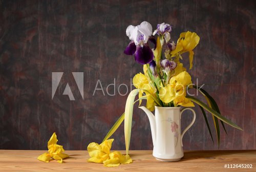 Yellow iris in a ceramic vase on a wooden table