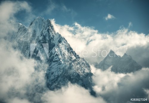 Manaslu mountain with snowy peak in clouds in sunny bright day in Nepal.