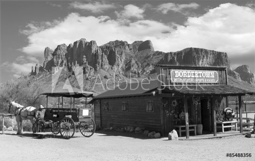Old black and white Wild West Cowboy town with horse drawn carriage and mountains in background