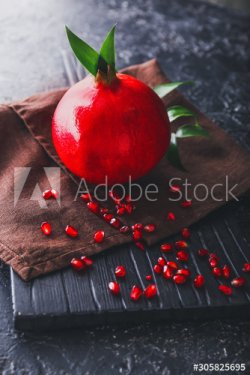 Board with tasty pomegranate on dark background - 901155357