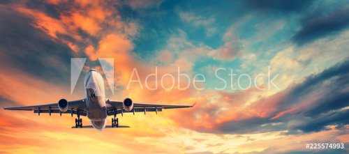 Landing airplane against colorful sky at sunset. - 901155224