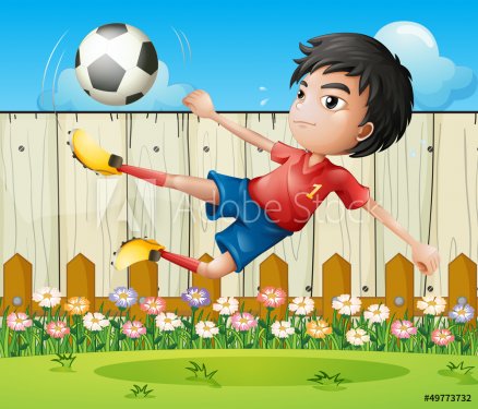 A boy playing soccer inside the fence