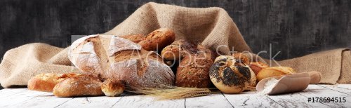 Assortment of baked bread and bread rolls on wooden table background. - 901152446