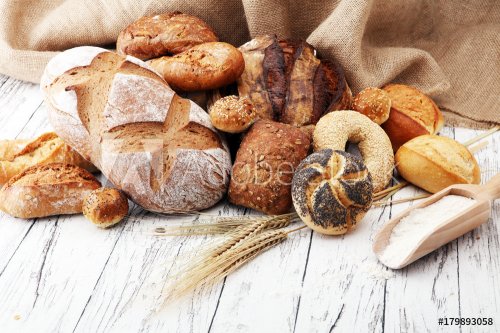 Assortment of baked bread and bread rolls on wooden table background. - 901152449