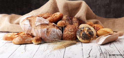 Assortment of baked bread and bread rolls on wooden table background. - 901152451