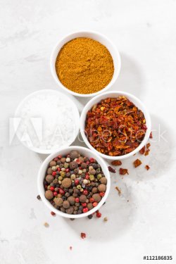 assortment of pepper, salt and spices in bowls, top view