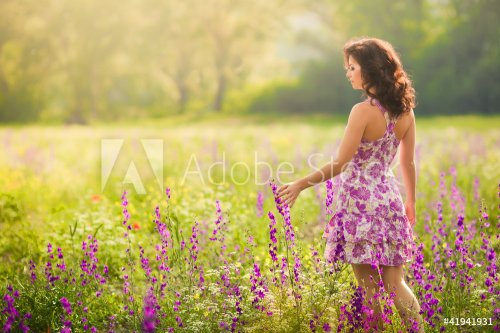 Beautiful young woman in purple flowers outdoors - 900429522