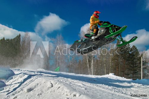 Big green Sport snowmobile jump. Cloud of snow dust from under snowmobile tracks. Concept extreme rest.