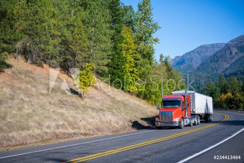 Big rig orange semi truck carry bulk semi trailer driving on winding road wit... - 901152651