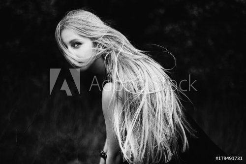 Blonde girl with very long hair on dark fone.Zhensky portrait. Conceptual photography. The girl's face is covered with hair.