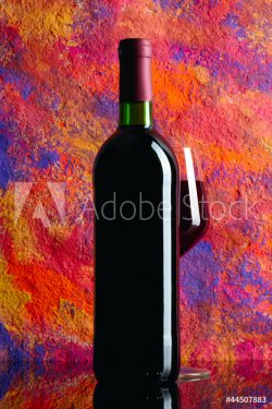 Bottle and glass with red wine over grange background