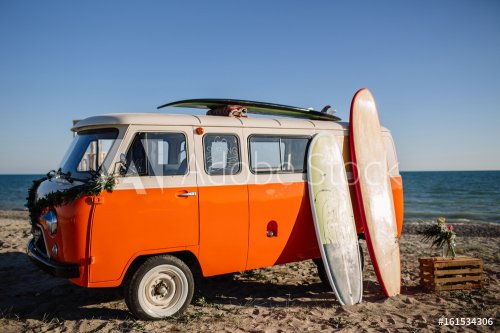 bus with a surfboard on the roof is a parked near the beach