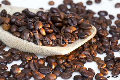 Coffee beans on wooden spoon and a white background