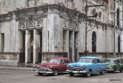 Cuban taxis passing under an old church in Havana