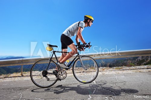 Cyclist riding a bike uphill along a road; clear summer day