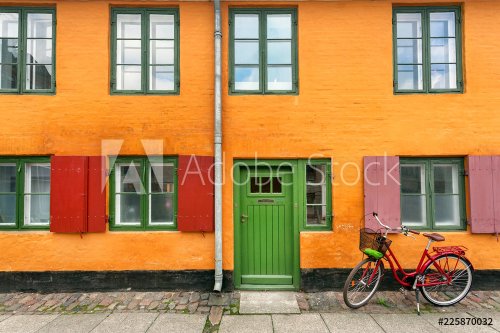 Female bicycle waiting for rider near yellow walls of historical building in traditional style of Copenhagen, Denmark. Old house on scandinavic city street