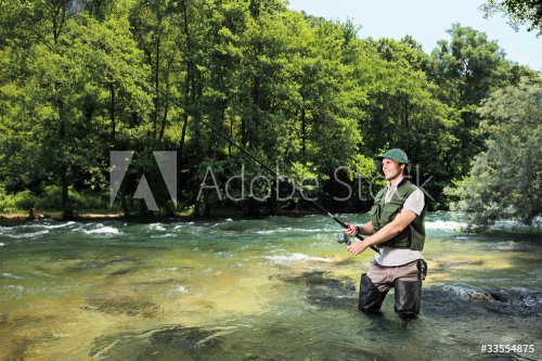 Fisherman fishing on a river with forest in the background - 900180718
