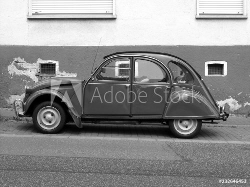 Französischer Kleinwagen Klassiker mit vier Türen und Rolldach vor einem alten Haus in Wettenberg Krofdorf-Gleiberg bei Gießen in Mittelhessen, fotografiert in neorealistischem Schwarzweiß