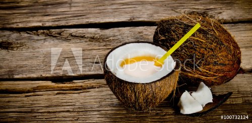 Fresh cocktail in coconut cup on wooden background. Free space for text.