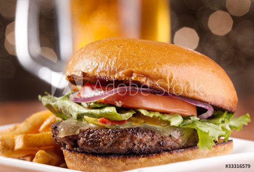 gourmet cheeseburger with mug of beer in background - 900251873