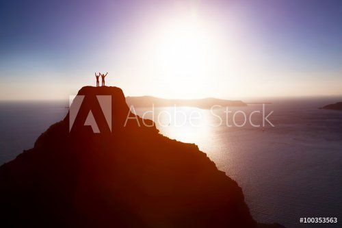 Happy couple on the top of the mountain over ocean celebrating life, success