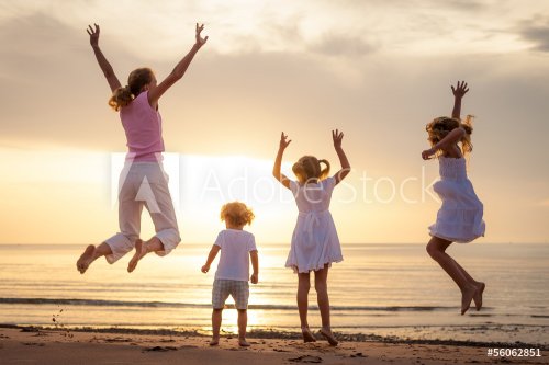 Happy family jumping on the beach on the dawn time - 901144131