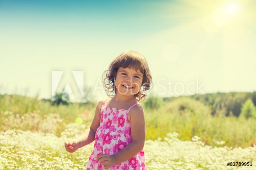 Happy little girl walks on the flower field