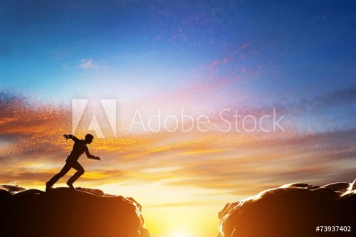 Man running fast to jump over precipice between two mountains - 901148953