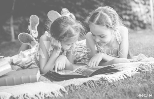 Monochrome photo of young girls looking at family photo album - 901144087