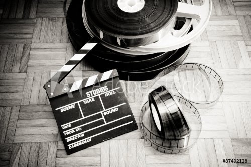 Movie clapper board and film reel on wooden floor