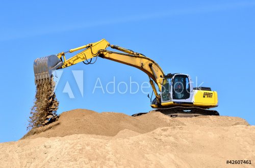 new yellow excavator working on sand dunes
