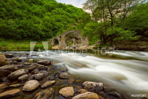 Old bridge through river with fast stream - 901144650