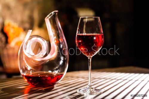 Red wine in a wine glass and carafe. Things placed on a wooden table