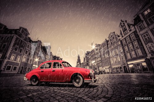 Retro red car on cobblestone historic old town in rain. Wroclaw, Poland.