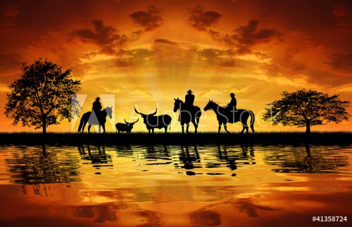 Silhouette cowboys on horses with cows in the sunset - 900458879