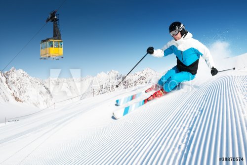 Skier in mountains, prepared piste and sunny day - 900479402