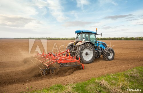 Small scale farming with tractor and plow in field - 900331763