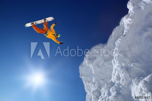 Snowboarder jumping against blue sky - 900224204