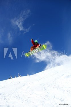 Snowboarder jumping against blue sky - 900454059