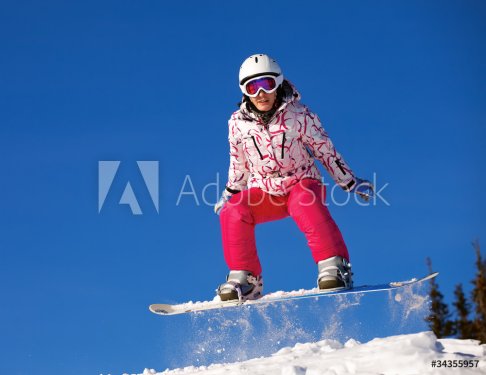 Snowboarder jumping through air with  blue sky in background - 900404305