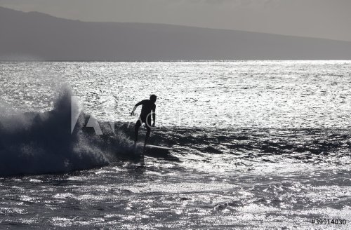 surfer silhoutted against the silver waves on maui coast - 901148772