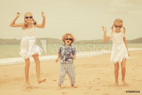 Three happy children dancing on the beach - 901144125