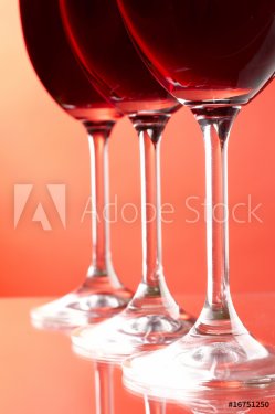 Three wine glasses on red background.