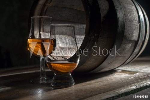 Two glasses of strong alcohol, amid oak barrels - 901147357